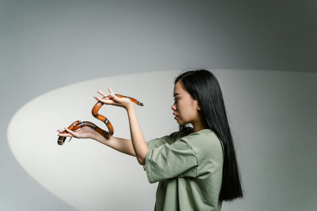 A woman confronting her fear by holding a snake, symbolizing overcoming anxiety.