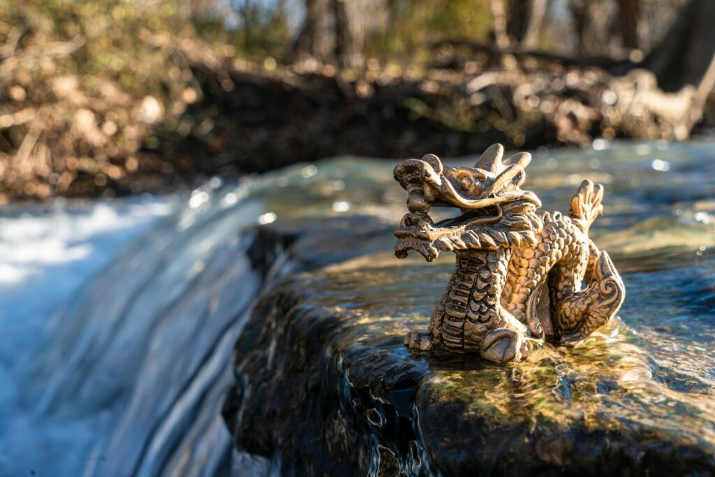 A gold-colored dragon figurine on a boulder on the river