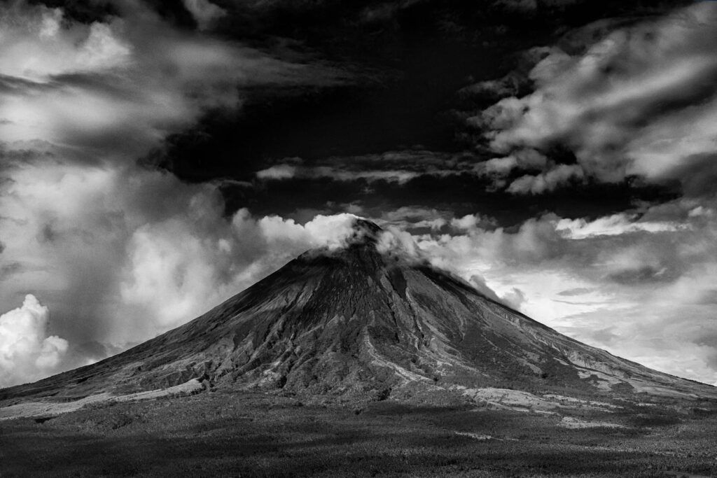 Dramatic black and white photo of Mayon Volcano with cloudy sky.